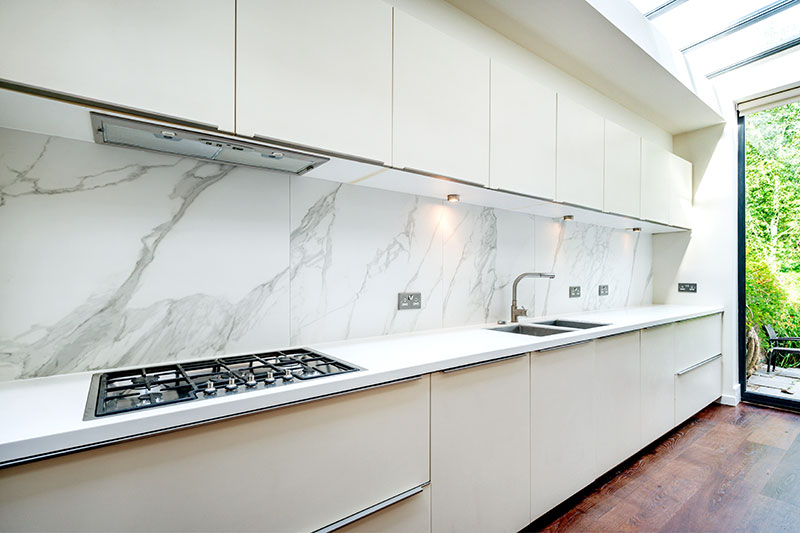 Handleless kitchen run with marble splashback, gas hob and integrated appliances