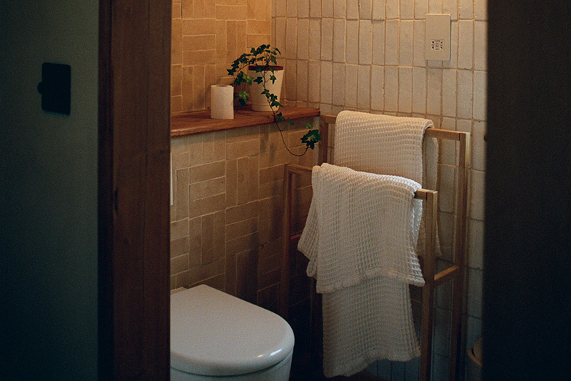 Cloakroom with handmade glazed wall tiles, timber shelf and towel ladder