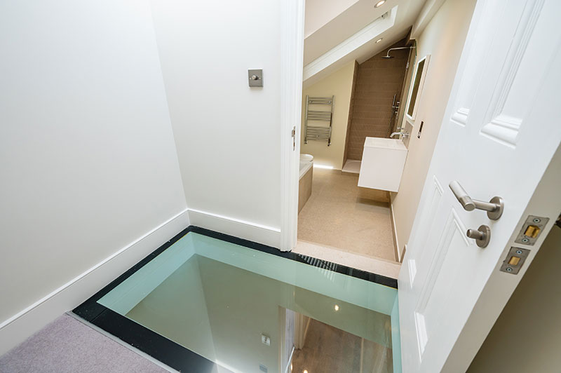 Landing with structural glass floor panel looking through to the loft bathroom