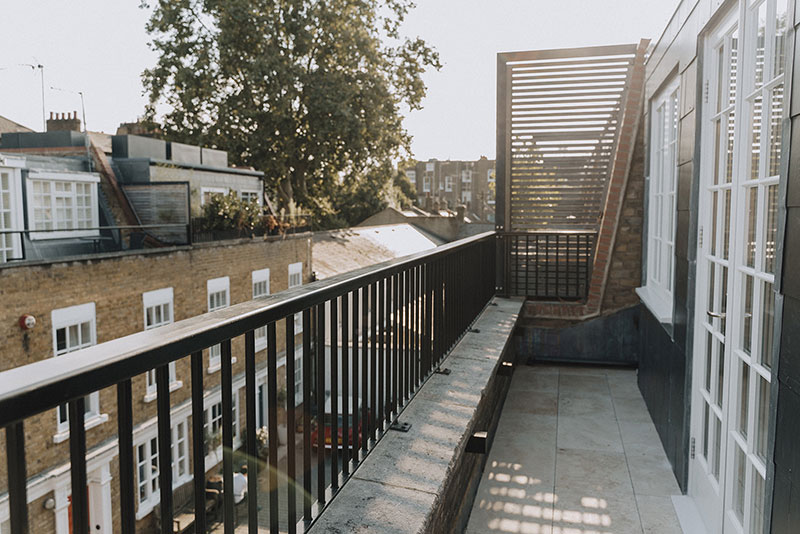 Roof terrace with metal balustrade and timber privacy screen over Notting Hill rooftops