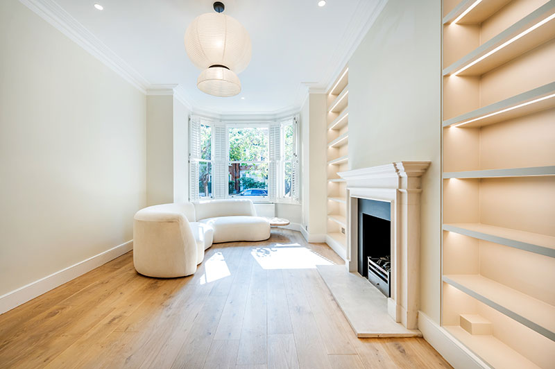Living room with bay window, stone fireplace and illuminated alcove shelving