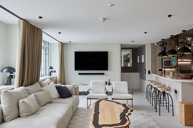 Living area with wall-mounted television, bespoke timber table and bar seating